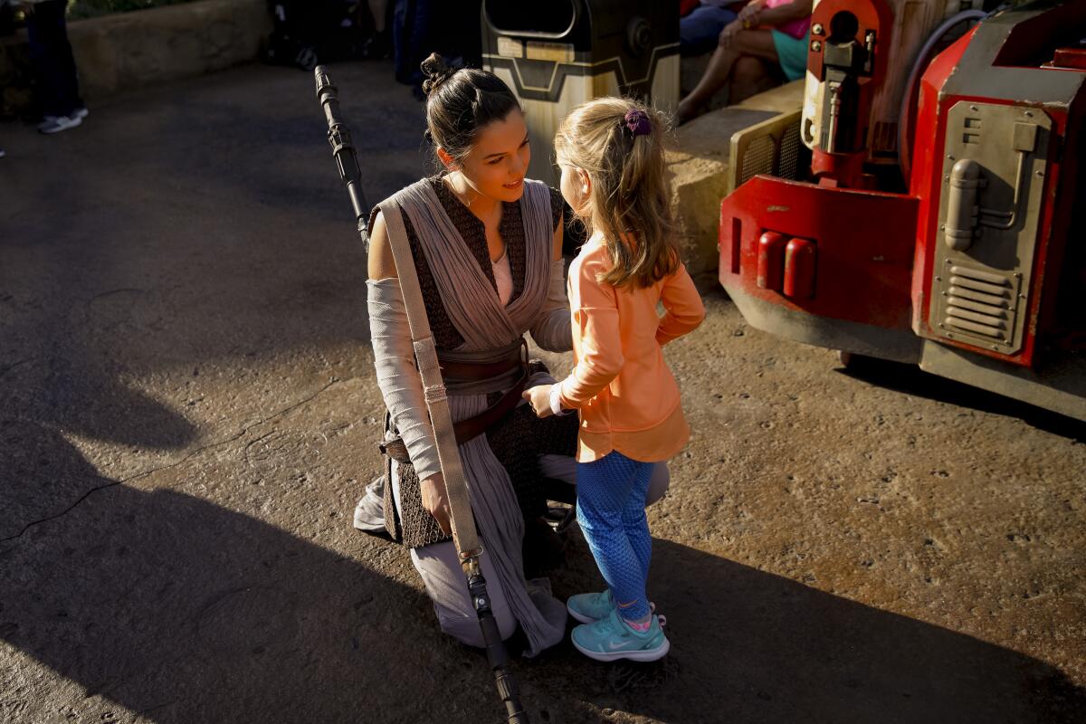 A cast member portraying Rey greets a young visitor at Star Wars: Galaxy’s Edge. 
