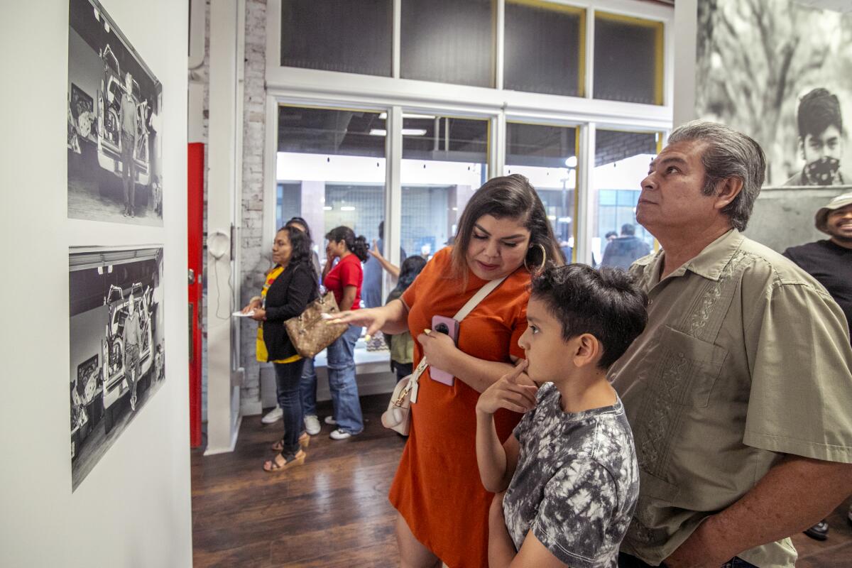 Karla Lawrernce explains a Jesus Cortez photo to 9-year-old Roger Orellana and his dad Victor.
