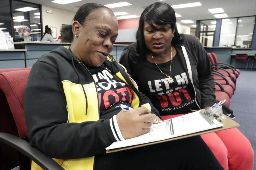 Gale Buswell watches her friend, former felon Yolanda Wilcox, fill out a voter registration form in Orlando, Fla., on Jan. 8.