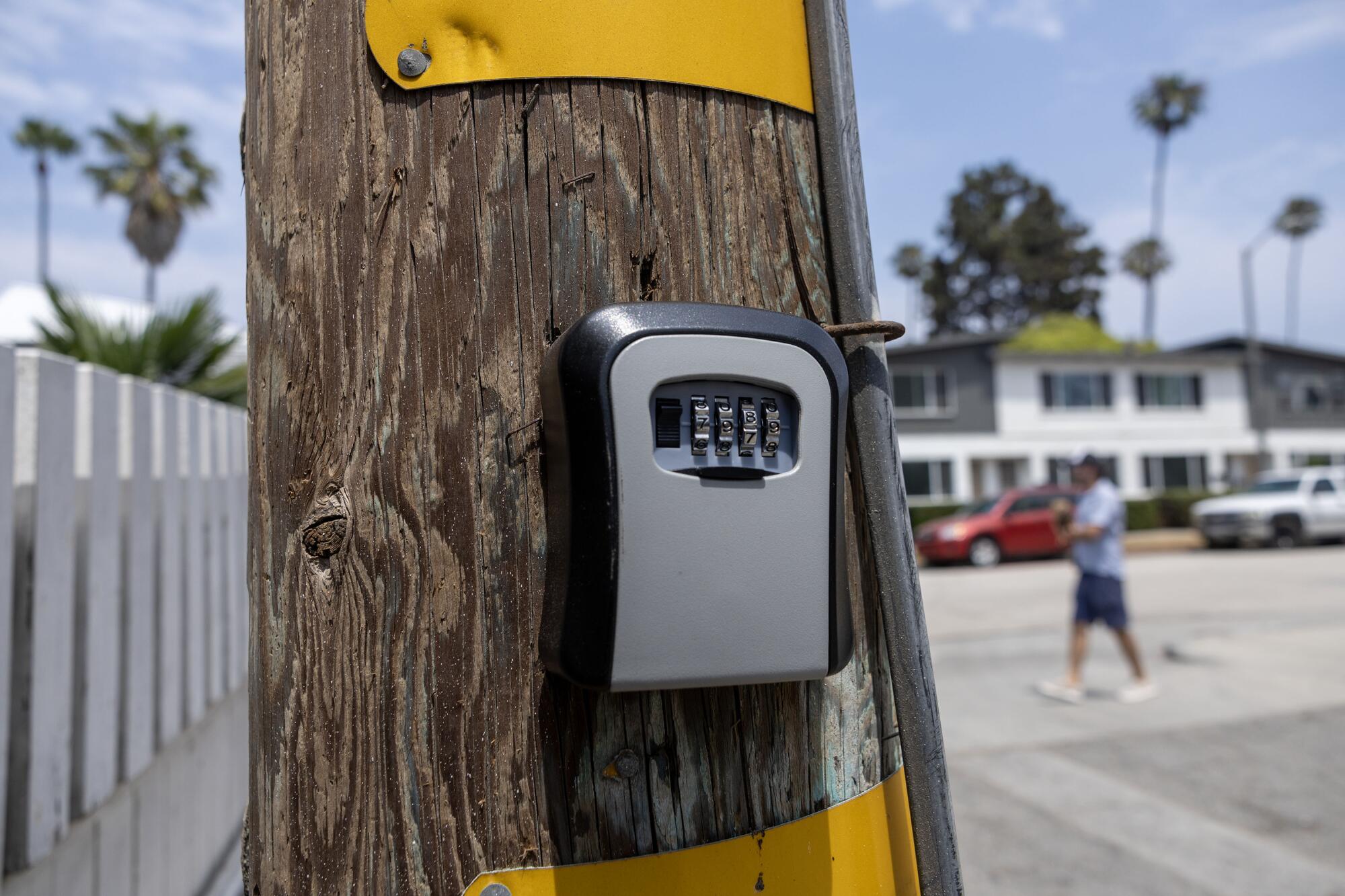 A combination lockbox for holding keys is fixed to a wooden utility pole.