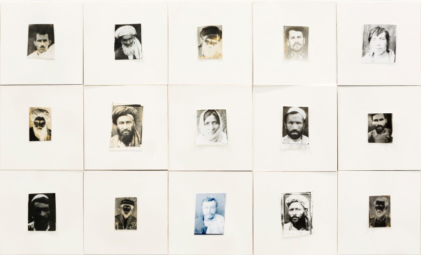 Rows of photos framed in large white rugs reveal the weary faces of Afghan citizens during the war