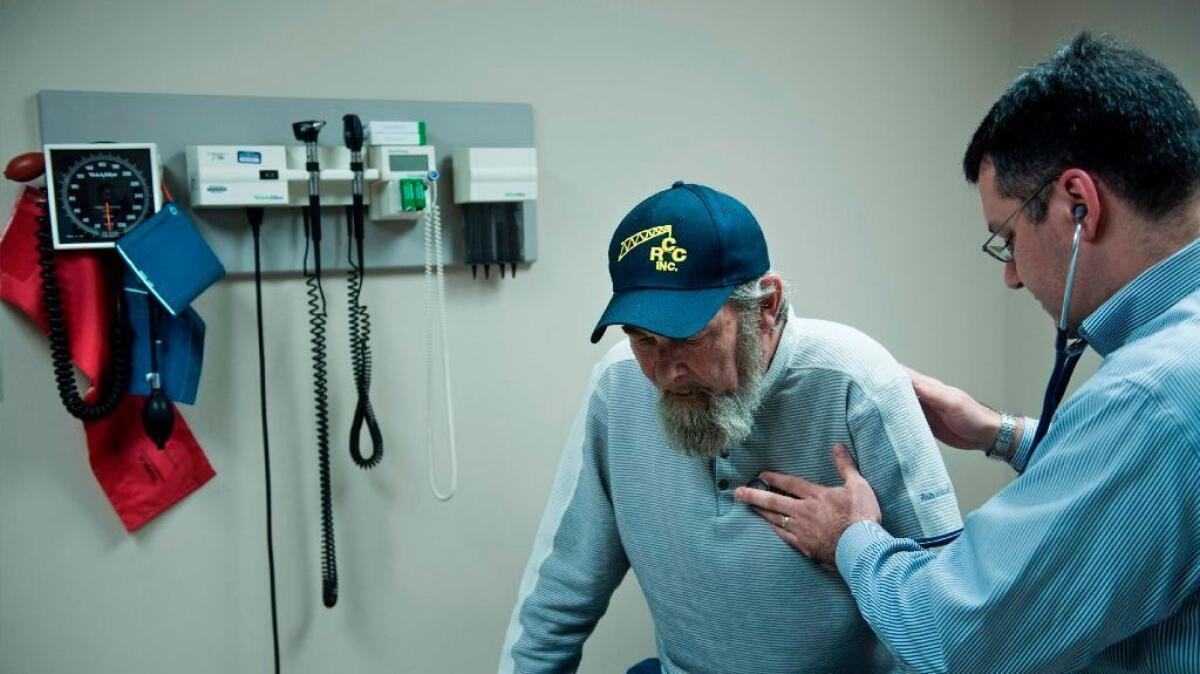 Don Humbertson, a 64-year-old lung cancer survivor, is examined by Dr. Wade Harvey at a community health center in Blacksville, W.Va.