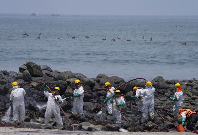 Workers continue in an oil clean-up campaign on Pocitos Beach in Ancon, Peru, Tuesday, Feb. 15, 2022. One month later, workers continue the clean-up on beaches after contamination by a Repsol oil spill. (AP Photo/Martin Mejia)