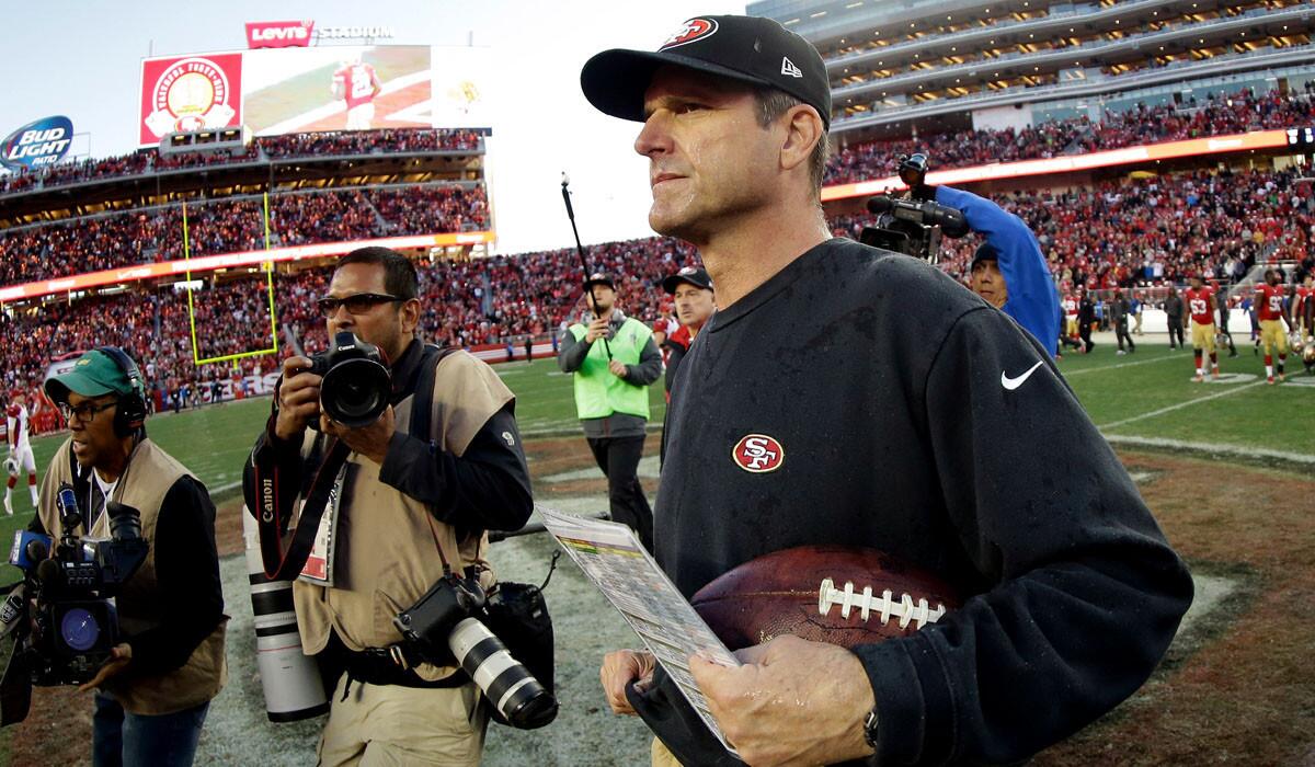 Jim Harbaugh carries the game ball off the field at Levi's Stadium after coaching the 49ers for the last time.