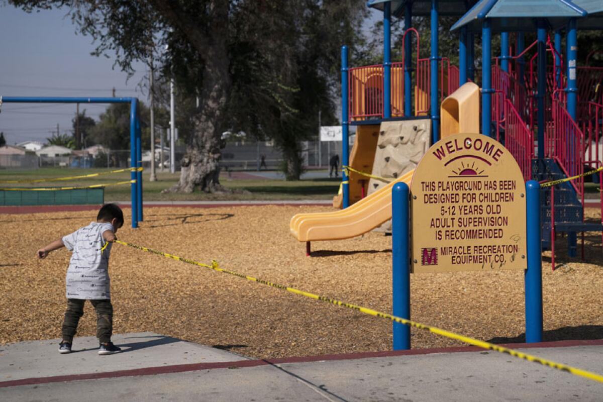 A boy pulls on caution tape at a Los Angeles playground that was closed because of the COVID-19 pandemic.