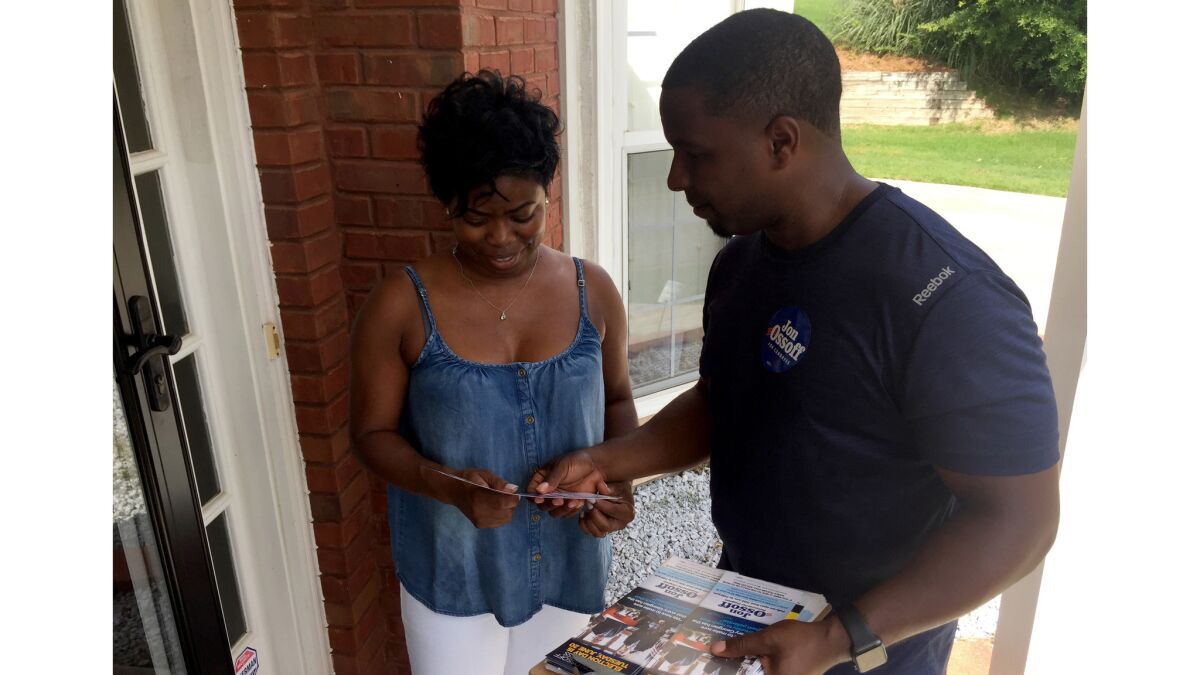 Marietta resident Charmetria Johnson talks outside her home with Donald Jumper, a political organizer with the congressional campaign of Democrat Jon Ossoff.