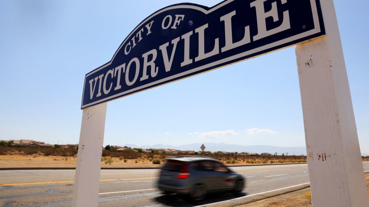 A car drives past a roadside sign for the city of Victorville