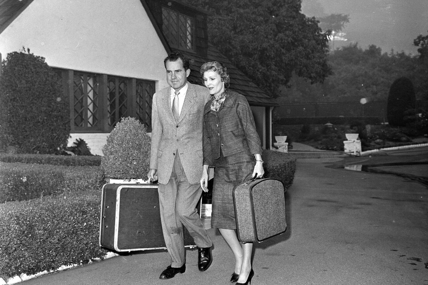 Richard and Pat Nixon carry suitcases as they evacuate their L.A. home during a fire