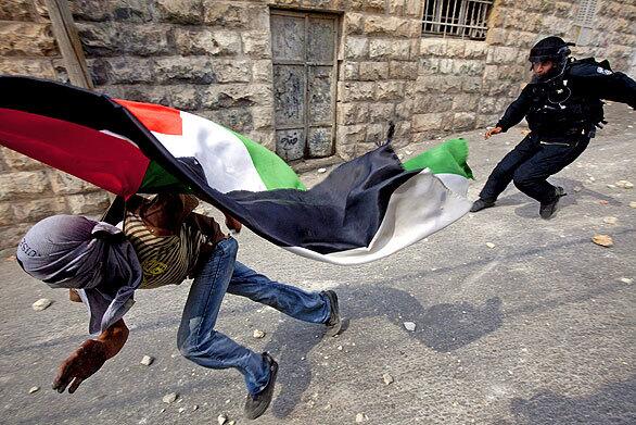 An Israeli policeman runs after a Palestinian stone-thrower in the Arab East Jerusalem neighborhood of Ras Amud on Friday. Israeli police tightly restricted access to Jerusalem's Old City as Palestinians went on strike in defense of the Al-Aqsa mosque compound following clashes at the site sacred to Muslims and Jews.