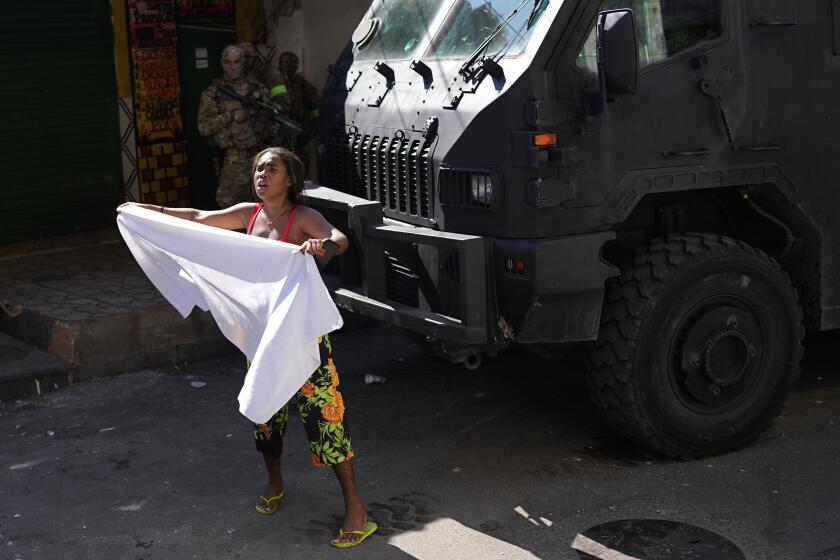 A resident waves a white sheet in protest and to ask for peace after a police operation that resulted in multiple deaths, in the Complexo do Alemao favela in Rio de Janeiro, Brazil, Thursday, July 21, 2022. Police said in a statement it was targeting a criminal group in Rio largest complex of favelas, or low-income communities, that stole vehicles, cargo and banks, as well as invaded nearby neighborhoods. (AP Photo/Silvia Izquierdo)