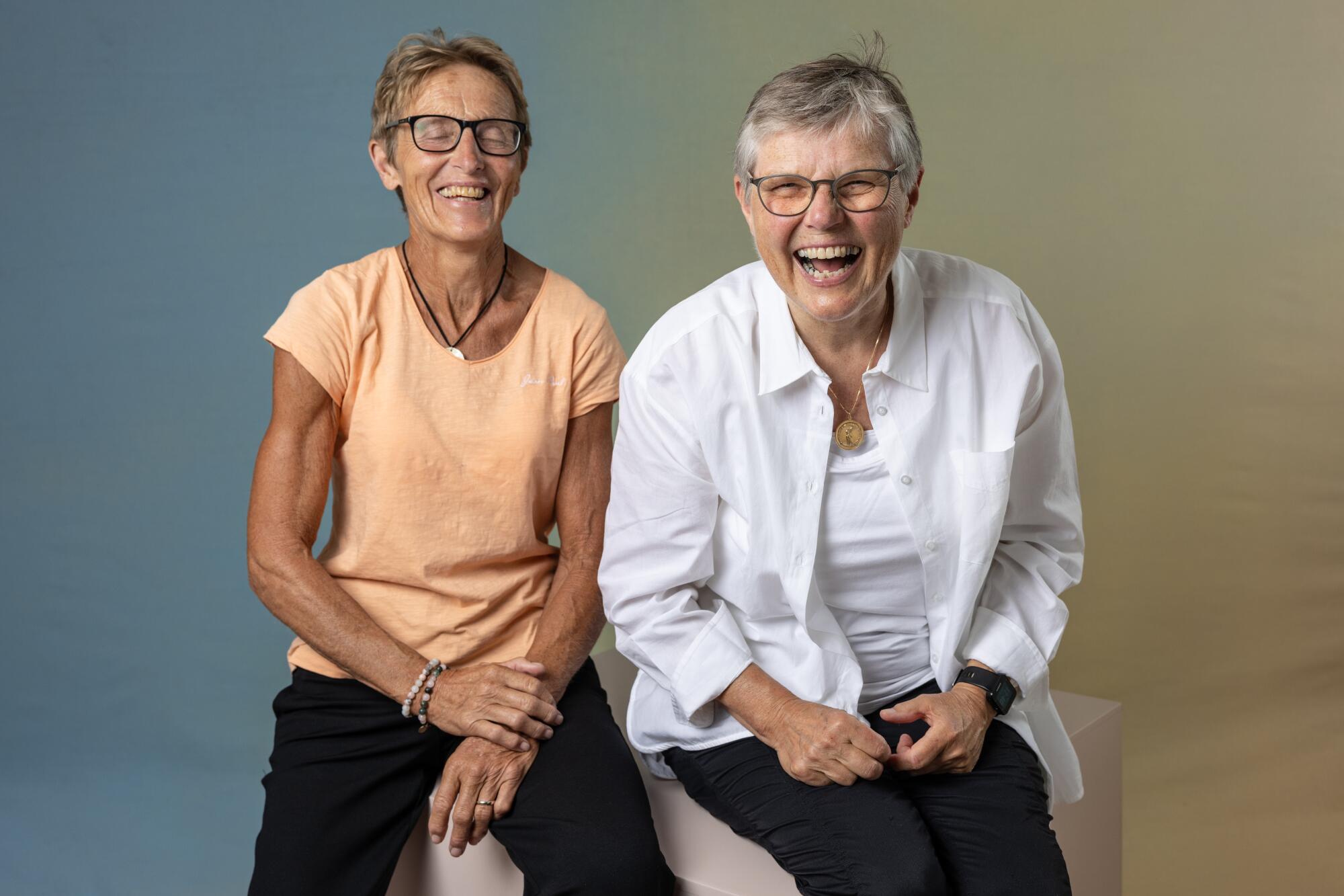Ann Stengaard and Birte Kjems sit on a cube and smile.