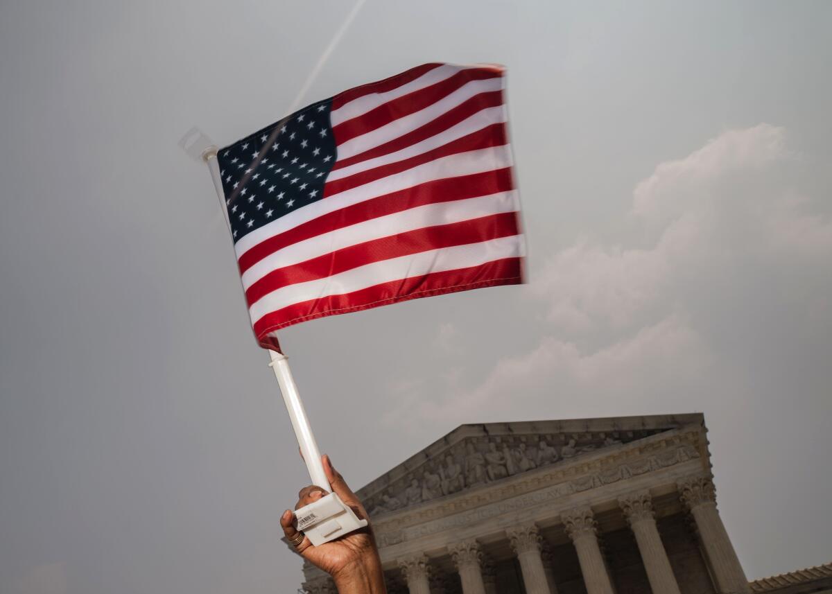 A woman holds an American flag during a rally outside of the Supreme Court 