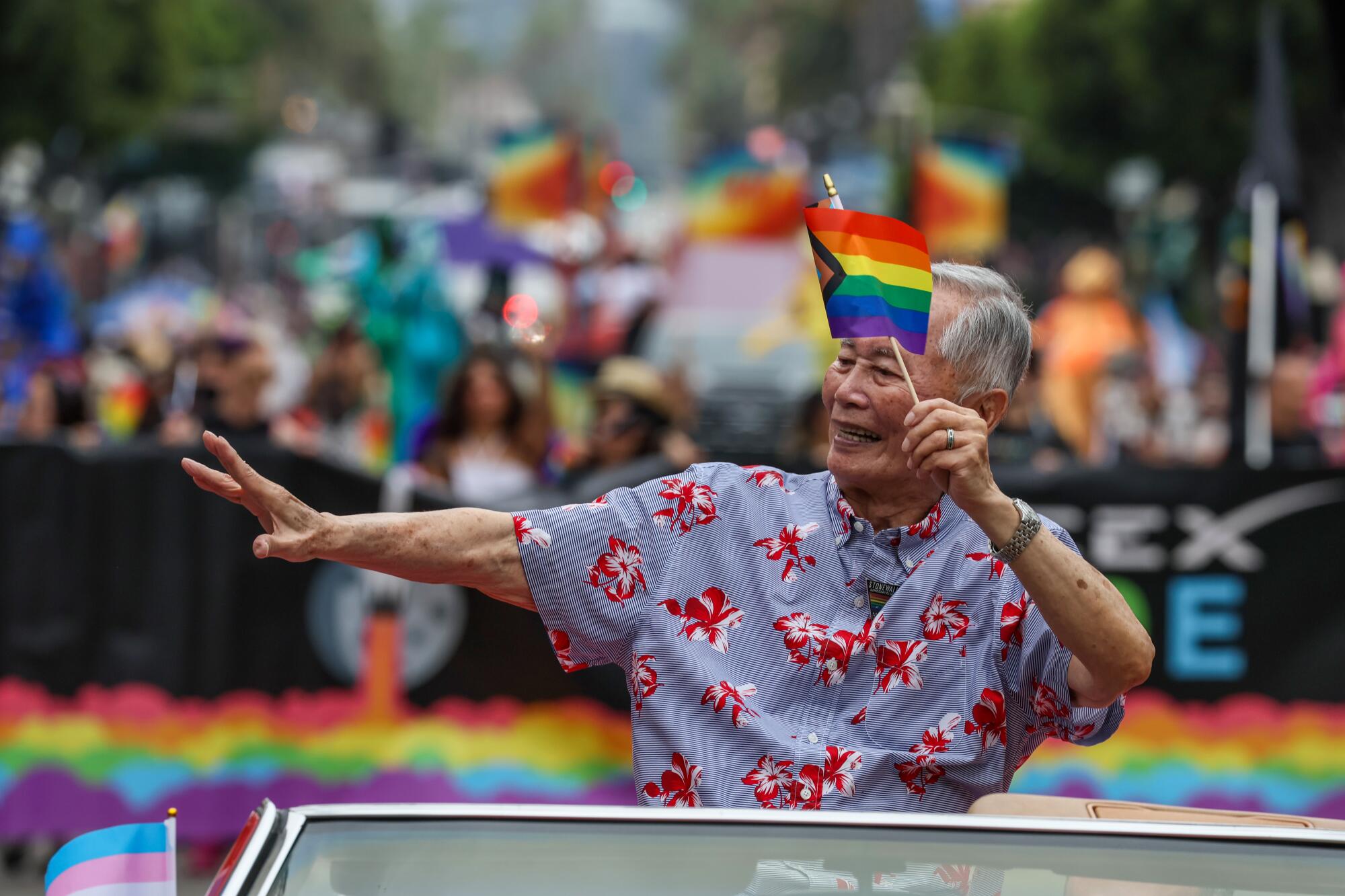 Actor George Takei waves to the crowd from his position in a convertible as grand marshal of the 2024 Los Angeles Pride Parade.