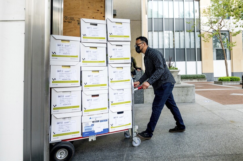 A member of Apple's legal team rolls exhibit boxes into the Ronald V. Dellums building in Oakland, Calif., as the company faces off in federal court against Epic Games on Monday, May 3, 2021. Epic, maker of the video game Fortnite, charges that Apple has transformed its App Store into an illegal monopoly. (AP Photo/Noah Berger)