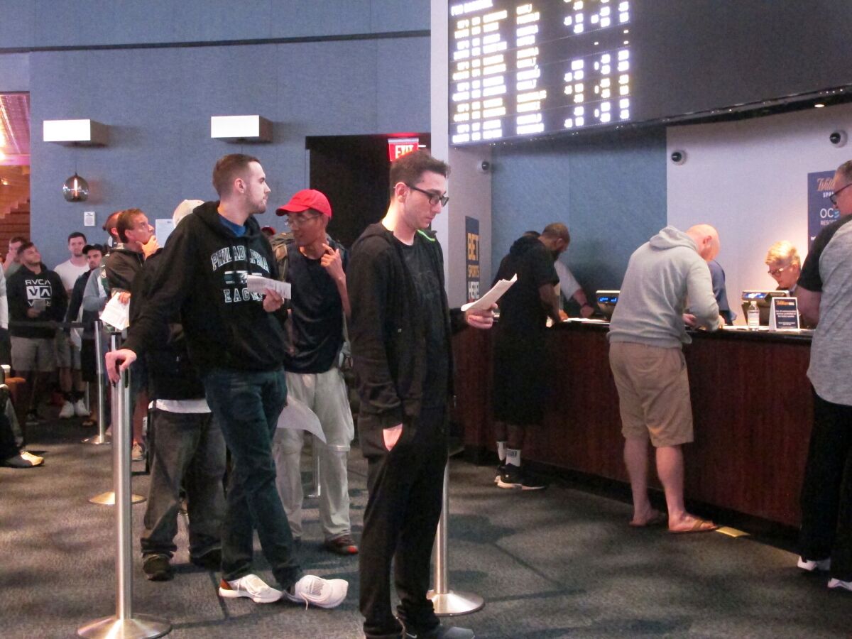 Customers line up to place wagers in the sports betting lounge at the Ocean Resort Casino in Atlantic City N.J. on Sept. 9, 2018. The coronavirus outbreak has added new wrinkles for bettors this year, but even so, the nation's sportsbooks expect a record year of bets on football in 2020 from an antsy public that has been cooped up for months amid the pandemic. (AP Photo/Wayne Parry)