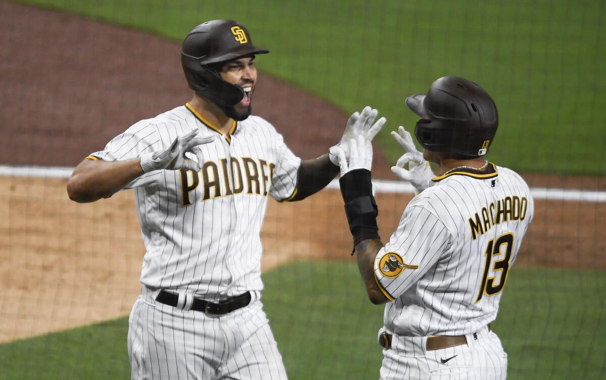San Diego Padres' Eric Hosmer, left, is congratulated by Manny Machado after hitting a two-run home run during the third inning of a baseball game against the Arizona Diamondbacks, Friday, April 2, 2021, in San Diego. (AP Photo/Denis Poroy)