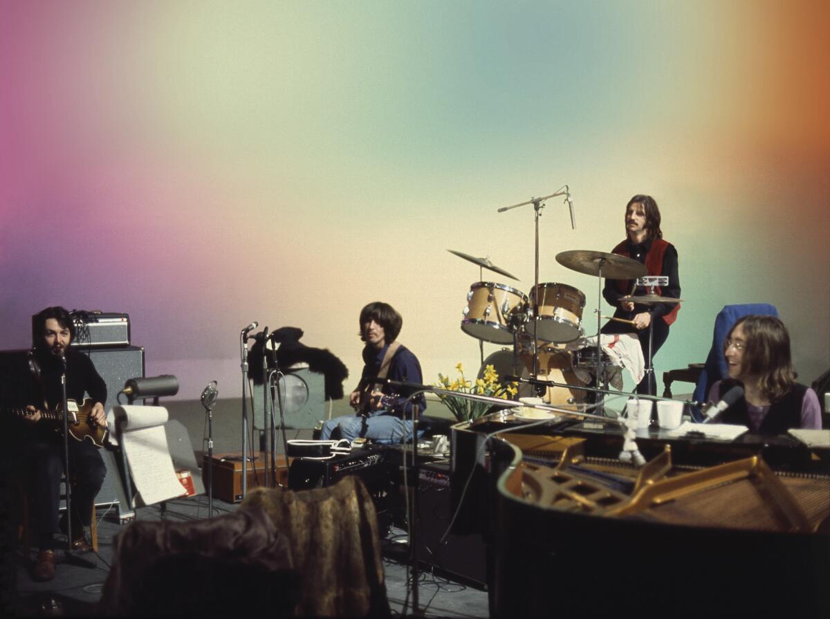 The Beatles perform before a multicolored screen.