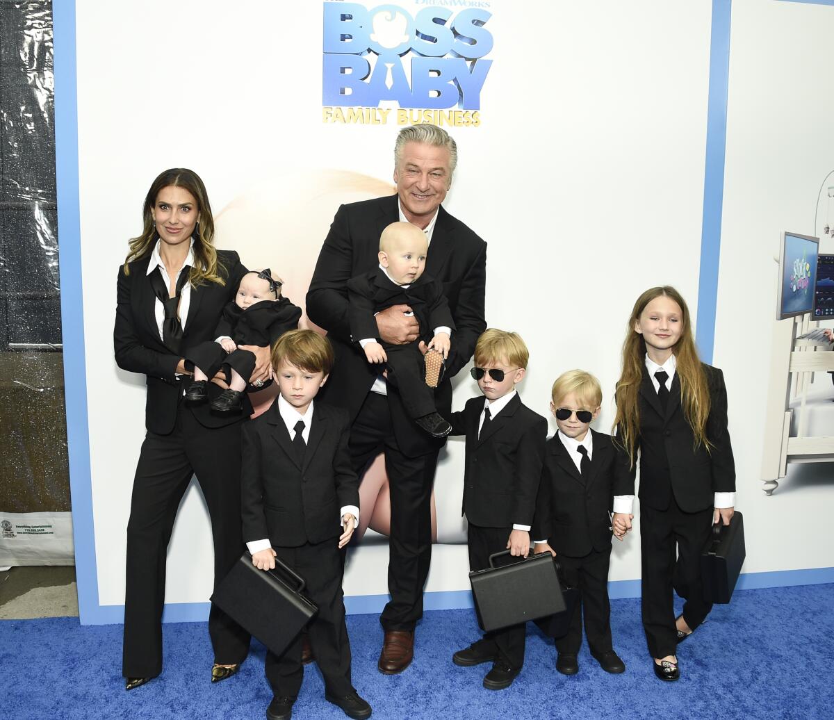 A family of eight poses in dark suits on a blue carpet for a movie premiere