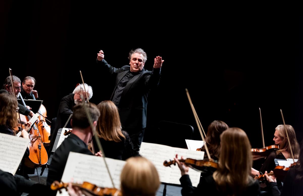 A man directs an orchestra in front of him.