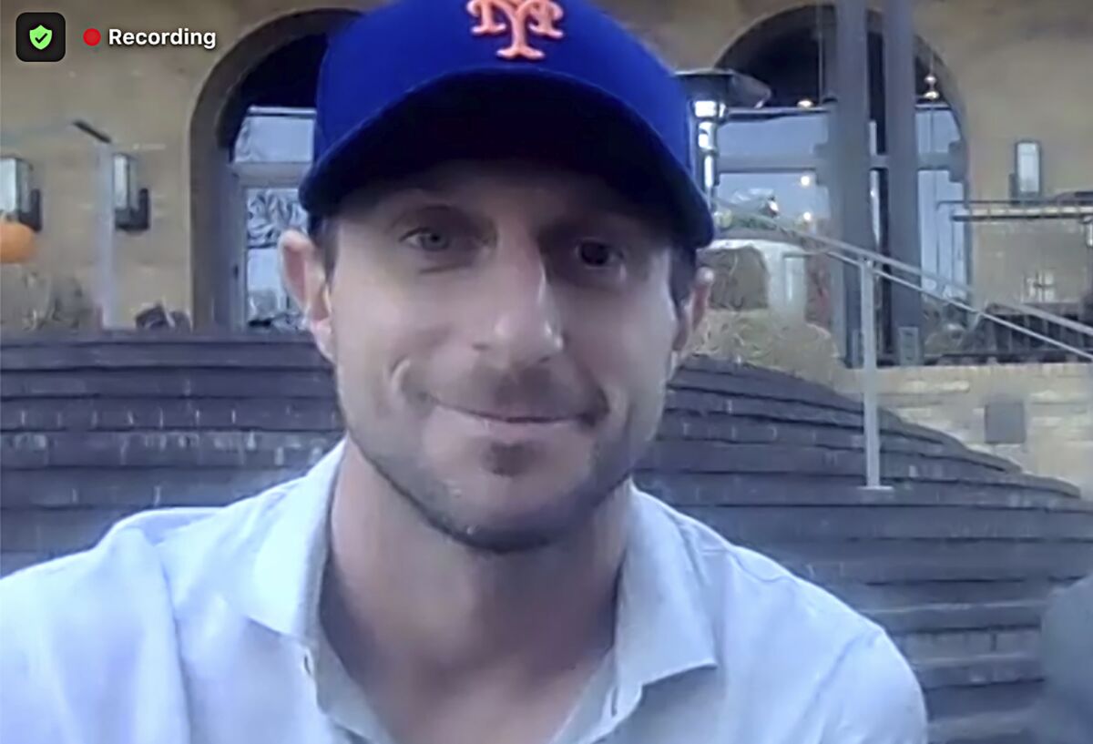 This still image from video shows New York Mets pitcher Max Scherzer in his new team cap during a news conference, Wednesday, Dec. 1, 2021. The Mets and the three-time Cy Young Award winner finalized a $130 million, three-year deal Wednesday, a contract that shattered baseball's record for highest average salary and forms a historically impressive 1-2 atop New York's rotation with Jacob deGrom. (New York Mets via AP)