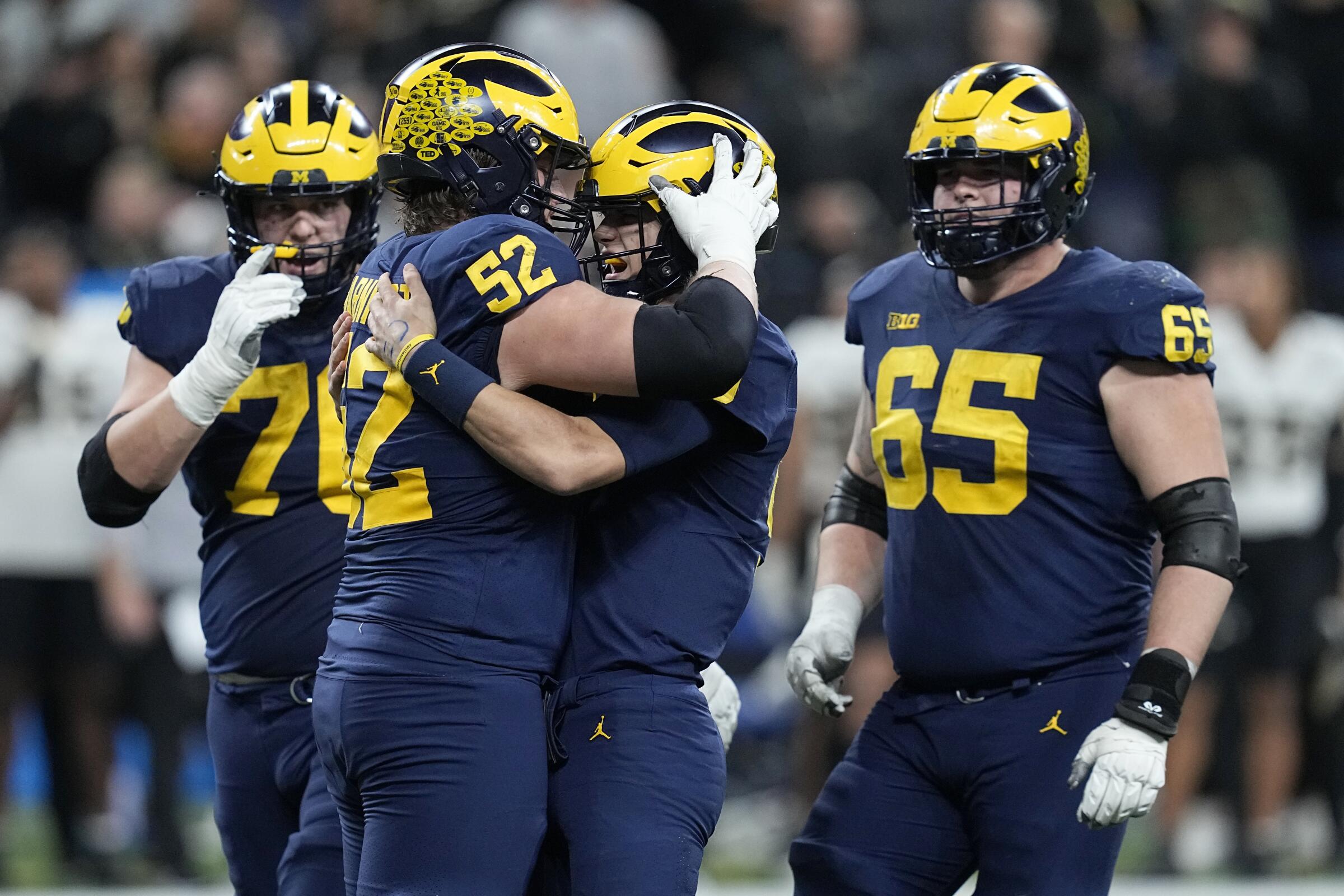 Michigan quarterback J.J. McCarthy, center, celebrates with his offensive linemen after throwing a touchdown pass.