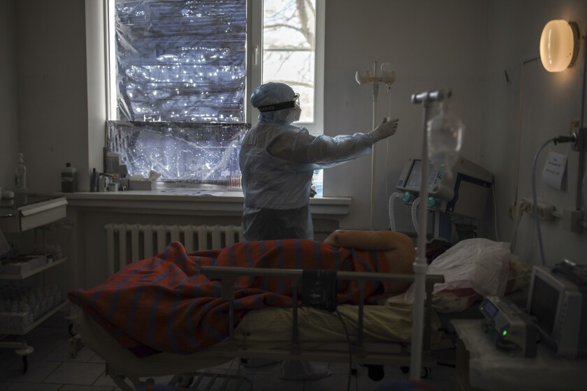Un paramédico con vestimenta especial trata a un enfermo de coronavirus en una UCI en la aldea de Poltavskaya, siur de Rusia, 25 de enero de 2022. Rusia ha habilitado vacunas para menores de 12 a 17 años mientras crece la oleada de infecciones a un paso sin precedentes. (AP Foto/Vitaliy Timkiv)