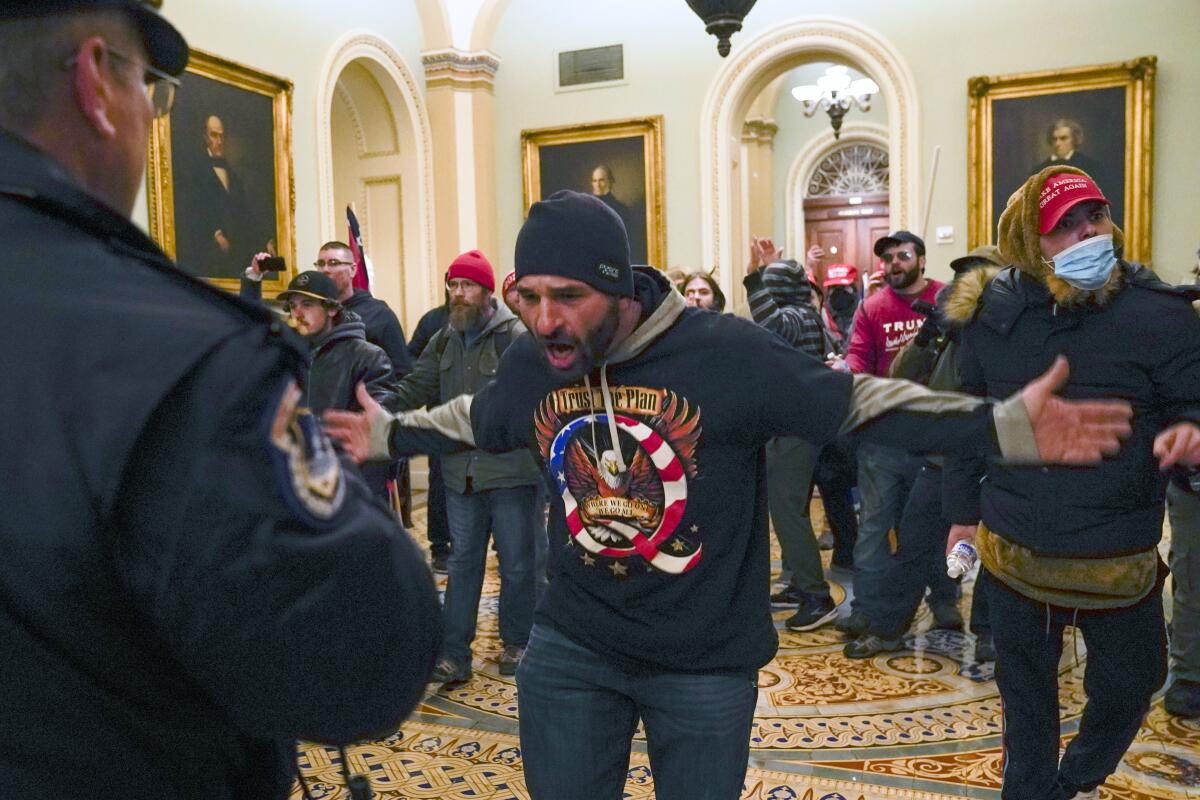 Rioter Doug Jensen gestures to U.S. Capitol Police in the hallway outside the Senate chamber at the Capitol Building.  