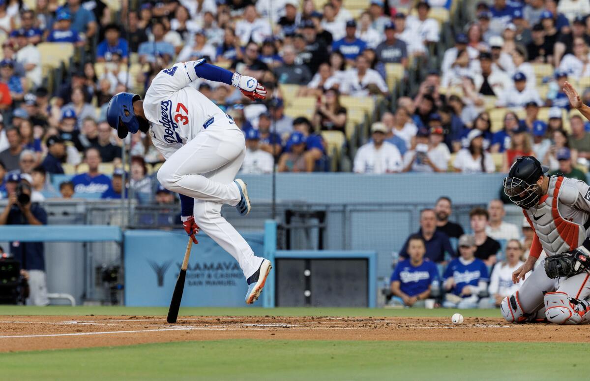 Dodgers outfielder Teoscar Hernández leaps out of the way after getting hit by a pitch thrown by the Giants' Robbie Ray.