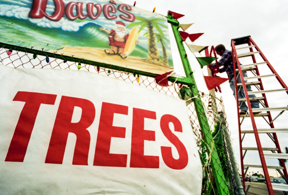 A person on a ladder next to a banner with an illustration of a Santa in shorts and holding a surfboard. 