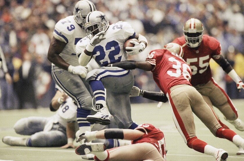 FILE - Dallas Cowboys running back Emmitt Smith (22) makes his way through San Francisco 49ers' defensive backs Merton Hanks (36) and Bill Romanowski (53), for a 4-yard gain in the second quarter of the Cowboy's 38-21 NFC championship win, Sunday, Jan. 23, 1994, in Irving, Texas. Few rivalries have had as many big games or star players like Roger Staubach, Joe Montana, Jerry Rice, Emmitt Smith, Deion Sanders, Steve Young, Troy Aikman and Michael Irvin. (AP Photo/Eric Gay, File)