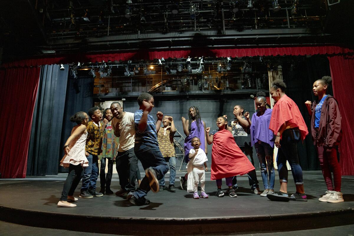 Kuumba Fest artistic director Dajahn Blevins (fourth from left) walks his cast through a scene during rehearsal at San Diego Rep.