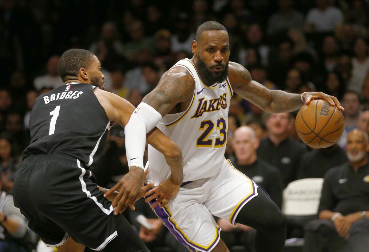 Lakers forward LeBron James, right, drives around Nets guard Mikal Bridges during the first half Sunday in Brooklyn.
