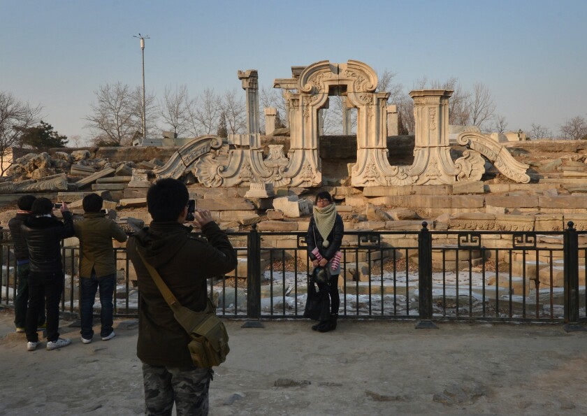 A woman poses for photos at the ruins of the Old Summer Palace in Beijing. In 1860, British and French troops burned it to the ground in an era the Chinese remember as a “century of humiliation."