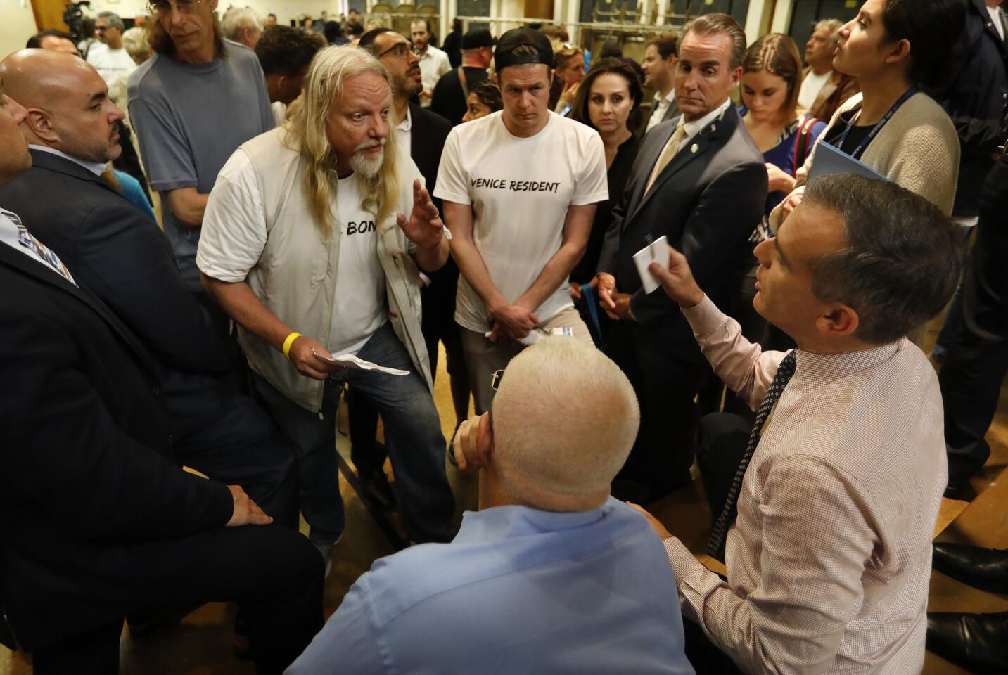 Rick Swinger, left, a 38 year resident of Venice, voices his opposition to put a homeless shelter in a vacant MTA lot in Venice, while talking to Councilman Mike Bonin, foreground, left, and Mayor Eric Garretti, right, during a town hall at Westminster Elementary School in Venice.