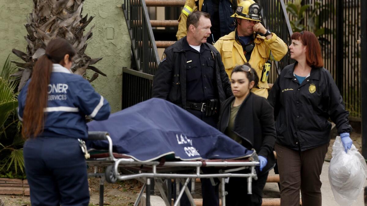 Coroner officials remove the body of a man discovered in the debris of an apartment fire in the 1500 block of Magnolia Avenue in Long Beach early Tuesday morning.