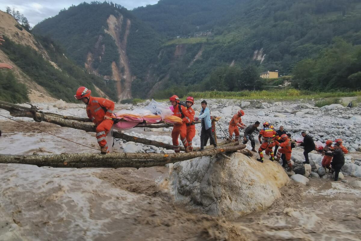 Rescue workers helping people cross a river in southwest China
