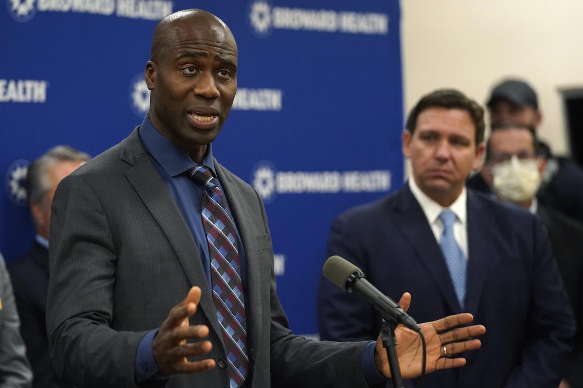 Florida Surgeon Gen. Dr. Joseph A. Ladapo, left, speaks at a news conference with Florida Gov. Ron DeSantis, right. 