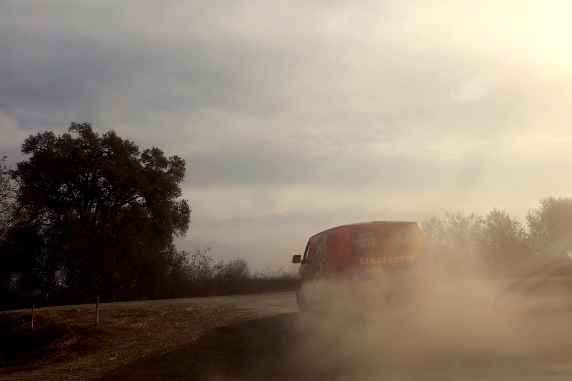Clouds of dust behind a van on a dirt road