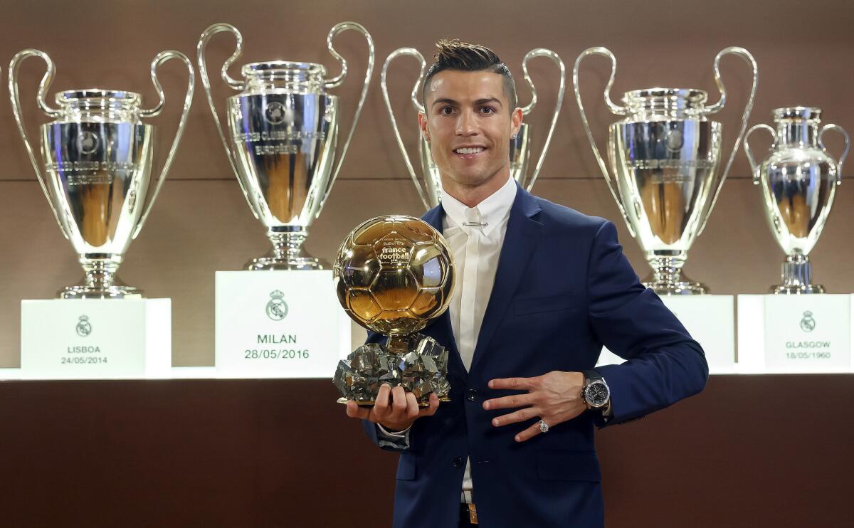 El jugador portugués del Real Madrid, Cristiano Ronaldo, posa con su cuarto Balón de Oro, ante otros trofeos del Real Madrid que están en la Sala de Juntas del estadio Santiago Bernabéu.
