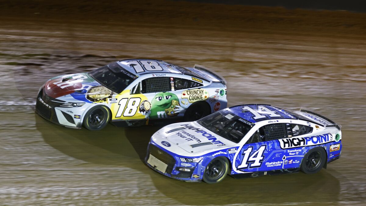 Driver Kyle Busch (18) races with Chase Briscoe (14) during a NASCAR Cup Series auto race, Sunday, April 17, 2022, in Bristol, Tenn. (AP Photo/Wade Payne)