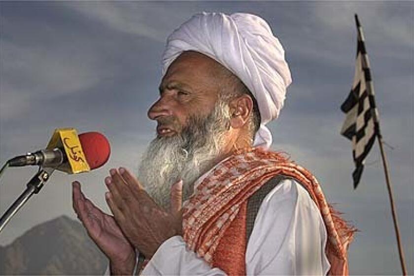 With white Taliban and striped party flags held by supporters, Maulana Noor Mohammed, right, prays at the stadium. His fundamentalist schools face closure or forced use of a secular curriculum.