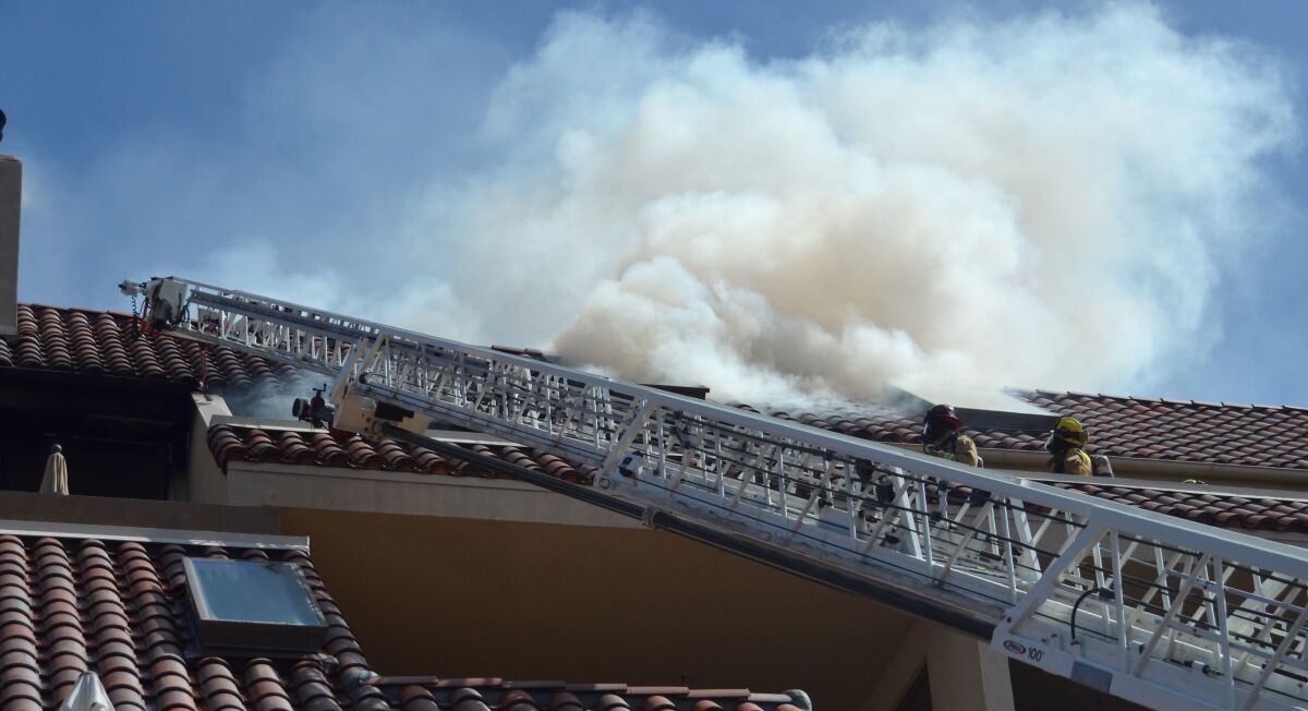 Smoke erupts from the roof during a four-alarm fire at Promontory Point apartment in Newport Beach.