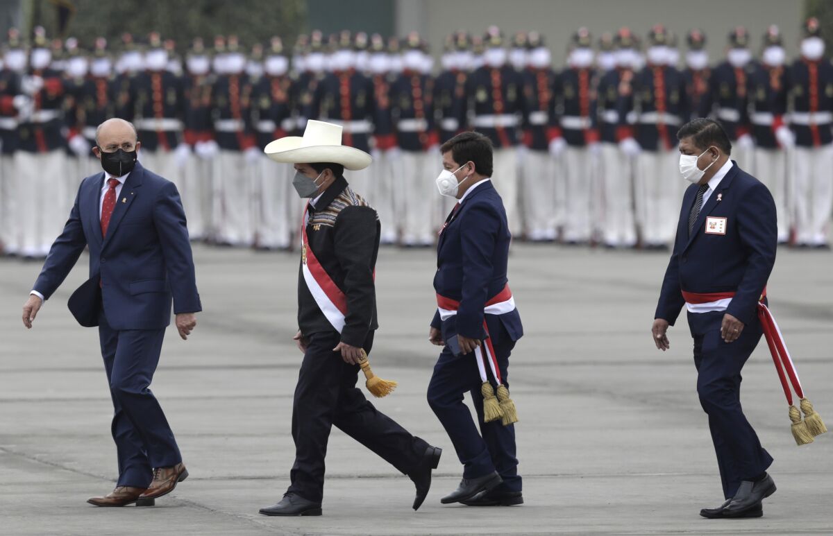 Peru's President Pedro Castillo, second from left, is followed by Prime Minister Guido Bellido and Defense Minister Walter Ayala at a military parade in Lima, Peru, Friday, July 30, 2021. (AP Photo/Guadalupe Pardo)