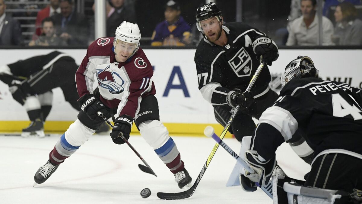 Colorado Avalanche left wing Matt Calvert, left, tries to shoot past Kings goaltender Cal Petersen, right, as center Jeff Carter reaches in during the first period.