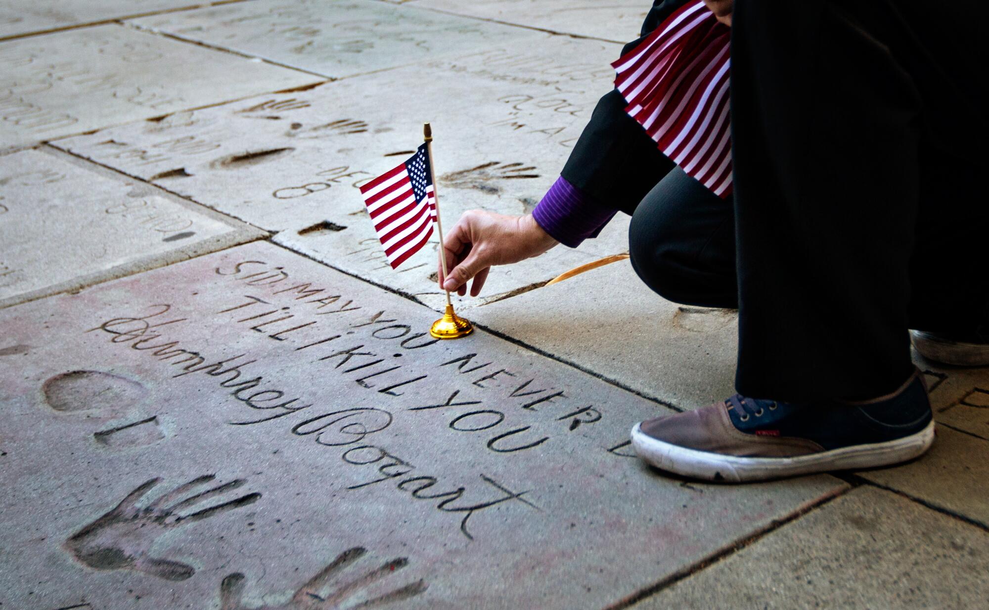 Levi Tinker places U.S. flag on Humphrey Bogart's square outside TCL Chinese Theatre in Hollywood.