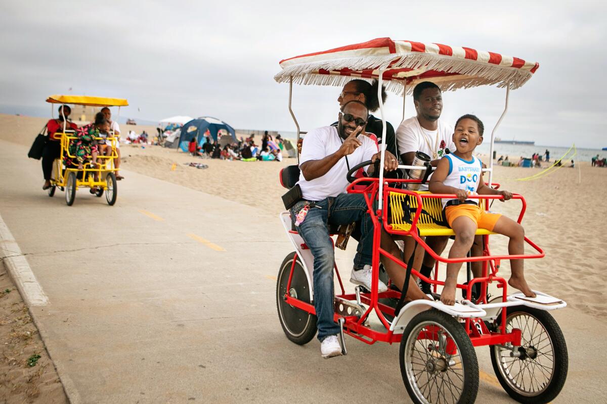 Families ride pedal cabs at the beach.