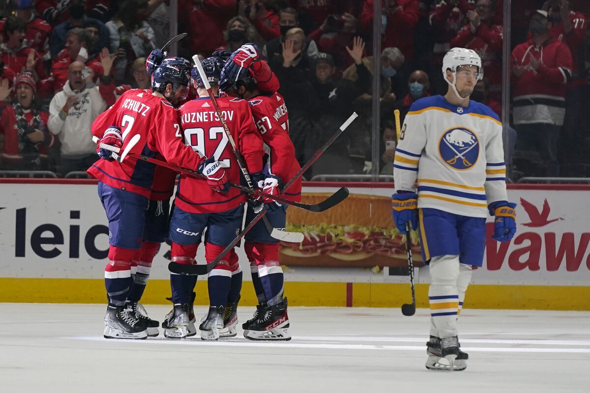 Members of the Washington Capitals celebrate Tom Wilson's goal in front of Buffalo Sabres defenseman Casey Nelson, right, in the first period of an NHL hockey game, Monday, Nov. 8, 2021, in Washington. (AP Photo/Patrick Semansky)