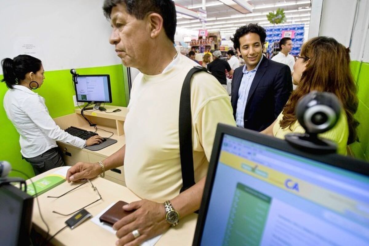 Progreso Financiero founder James Gutierrez, second from right, chats with a customer while her husband makes a payment at a kiosk in a supermarket. Gutierrez's new company, Insikt, enables other businesses to provide loans to customers with limited credit histories.
