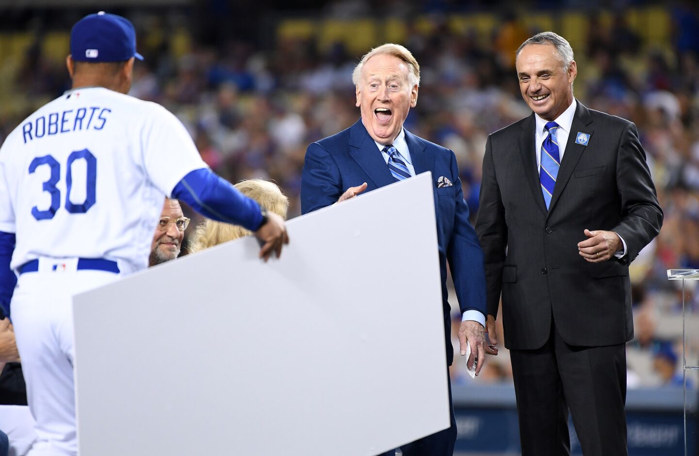 Dodgers Manager Dave Roberts (30) joins MLB Commissioner Rob Manfred, right, in presenting a check to Vin Scully to be donated to the Dodgers broadcaster's favorite charity during a pregame ceremoney Sept. 23, 2016.