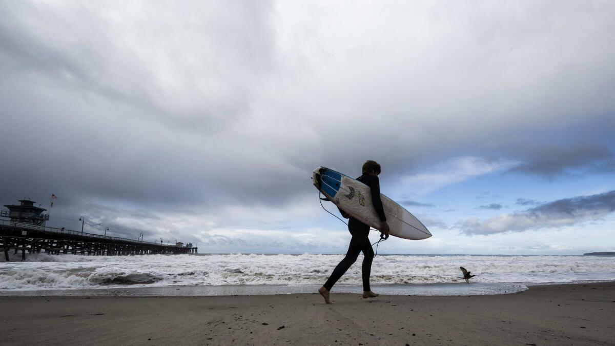  A surfer heads to the water as storms move through the area in San Clemente, Calif., Dec. 12, 2022.  